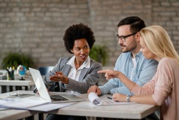 black female insurance agent using computer with couple during consultations office